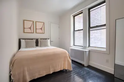 a white bedroom with a bed and two windows at Midtown 2br w doorman wd nr Central Park NYC-1246 in New York