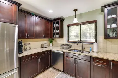 a kitchen with wooden cabinets and a stainless steel refrigerator at Pocono Pines Gem with Fire Pit and On-Site Creek! in Pocono Pines