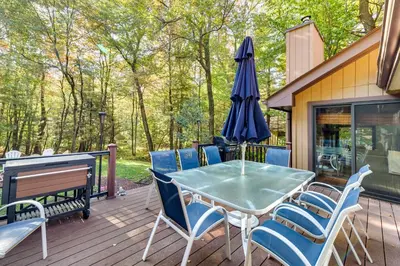 a patio with a table and chairs and an umbrella at Pocono Pines Gem with Fire Pit and On-Site Creek! in Pocono Pines