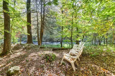 two wooden benches sitting in the woods at Pocono Pines Gem with Fire Pit and On-Site Creek! in Pocono Pines