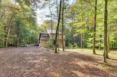 a house in the middle of a forest at Pocono Pines Gem with Fire Pit and On-Site Creek! in Pocono Pines