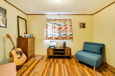 a living room with a blue chair and a guitar at Hike, Swim, Ski and More Home in Arrowhead Lakes! in Pocono Lake