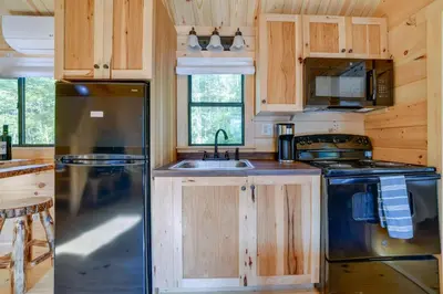 a kitchen with wooden cabinets and a stainless steel refrigerator at Catskills Tiny Home Cabin Surrounded by Nature! in Franklin