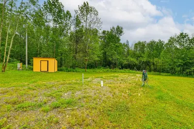 a large field with a yellow shed in the distance at Catskills Tiny Home Cabin Surrounded by Nature! in Franklin