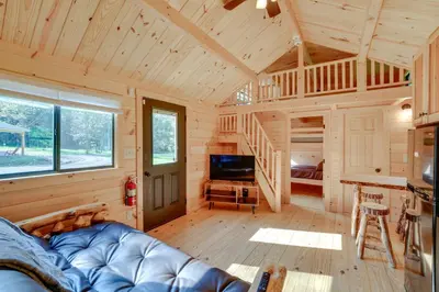 a living room with a blue couch in a log cabin at Catskills Tiny Home Cabin Surrounded by Nature! in Franklin