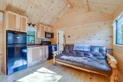 a living room with a leather couch in a log cabin at Catskills Tiny Home Cabin Surrounded by Nature! in Franklin