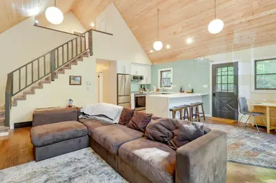 a living room with a brown couch and a kitchen at Community Beach Access Modern Poconos Cabin! in Albrightsville