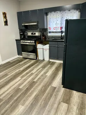 a kitchen with black cabinets and a wooden floor at Iron Bound Gem in Newark
