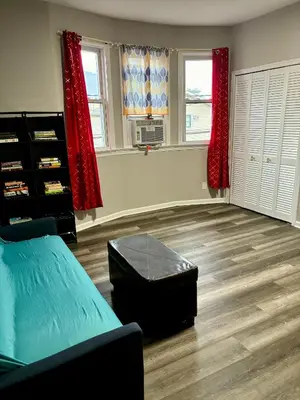 a living room with a bed and a table and windows at Iron Bound Gem in Newark