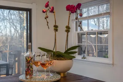 a table with two glasses of wine and a vase with flowers at Hudson Valley Cottage Rental 3 bedrooms Monroe NY in Monroe