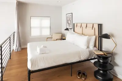 a bedroom with a bed and a lamp and a chair at Sosuite at The Vine - Old City in Philadelphia