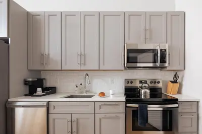 a kitchen with white cabinets and a stove and microwave at Sosuite at The Vine - Old City in Philadelphia