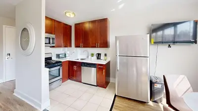 a kitchen with wooden cabinets and a stainless steel refrigerator at Avenue A310 Furnished 2br With Pool And Gym in Philadelphia