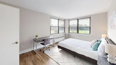 a bedroom with a bed and a desk and windows at Avenue A310 Furnished 2br With Pool And Gym in Philadelphia