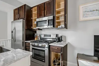 a kitchen with stainless steel appliances and wooden cabinets at Charming HBG Haven: Cozy 1BR Apt in Harrisburg