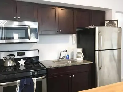 a kitchen with black cabinets and a stainless steel refrigerator at Skyline 3BR 20 MIN to T Square #2 in West New York