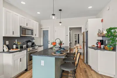 a kitchen with white cabinets and a island with bar stools at Passyunk Square Spacious 1 BR Oasis- Huge Deck in Philadelphia