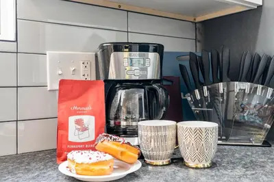 a counter with a coffee maker and two donuts and cups at E Passyunk Ave 1 BR Gem - Prime Location! in Philadelphia