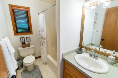 a bathroom with a sink and a toilet and a mirror at Serenity Falls - Stylish 4Bdr Mountain Retreat, Hot Tub, Pool in East Stroudsburg