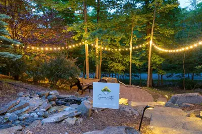 a sign in front of a fire pit with lights at Serenity Falls - Stylish 4Bdr Mountain Retreat, Hot Tub, Pool in East Stroudsburg