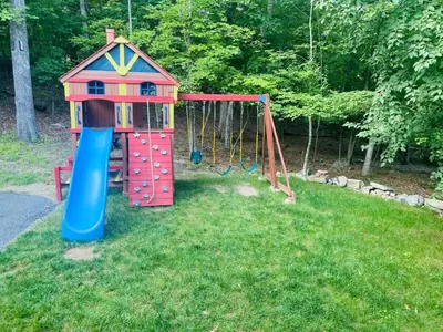 a playground with a slide and a swing at Serenity Falls - Stylish 4Bdr Mountain Retreat, Hot Tub, Pool in East Stroudsburg