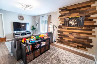a living room with a couch and a dart board on a wall at Serenity Falls - Stylish 4Bdr Mountain Retreat, Hot Tub, Pool in East Stroudsburg