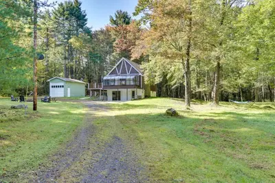 a house in the middle of a field with trees at Glen Spey Cabin with Deck 1 Mi to Mohican Lake! in Glen Spey
