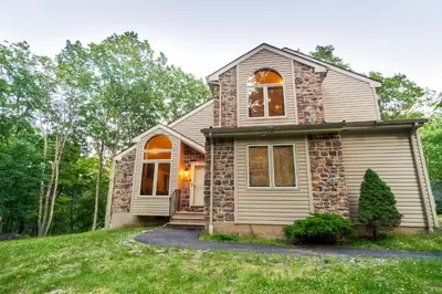 a house on a hill with trees in the background at Harmony Hill Stylish 4bd Mountain Retreat, Hot Tub, Games in Bushkill