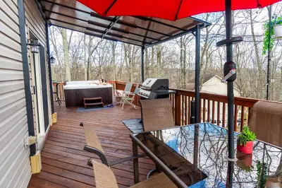 a patio with a table and an umbrella on a deck at Harmony Hill Stylish 4bd Mountain Retreat, Hot Tub, Games in Bushkill