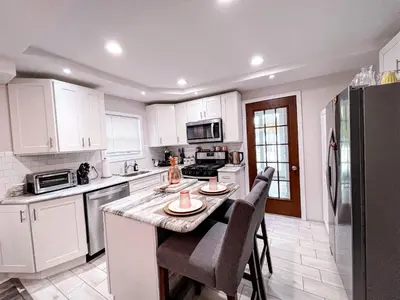 a kitchen with white cabinets and a table with chairs at Cheerful & Modern Home w/ a Walkout Deck Area in Glenside