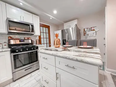 a kitchen with white cabinets and stainless steel appliances at Cheerful & Modern Home w/ a Walkout Deck Area in Glenside