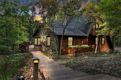 a cabin in the woods with a wooden walkway at Star Gazer Luxury A-Frame Wood Cabin. Near York/Harrisburg/Hershey/Lancaster in Goldsboro