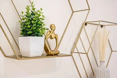 a gold metal shelf with a statue next to a plant at Charming Home In Heart of City With King Size Bed! in Philadelphia