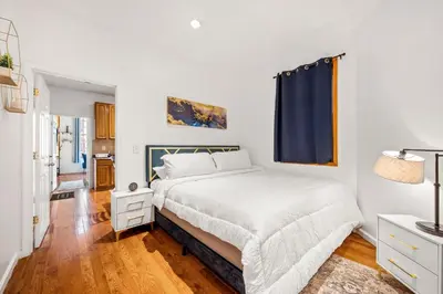 a white bedroom with a bed and a blue curtain at Charming Home In Heart of City With King Size Bed! in Philadelphia