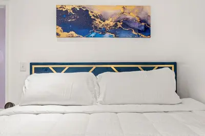 a bedroom with a white bed with a painting above it at Charming Home In Heart of City With King Size Bed! in Philadelphia