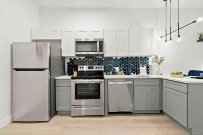 a kitchen with white cabinets and stainless steel appliances at Contemporary Luxury BR, EWR AIRPT, Nyc, Free Pkng, Prudential CNTR, American Dream Mall in Elizabeth
