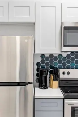 a kitchen with white cabinets and a stainless steel refrigerator at Contemporary Luxury BR, EWR AIRPT, Nyc, Free Pkng, Prudential CNTR, American Dream Mall in Elizabeth