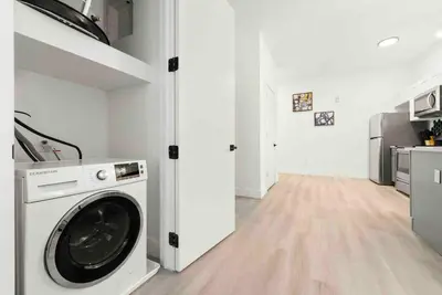 a washing machine in a white room with a kitchen at Contemporary Luxury BR, EWR AIRPT, Nyc, Free Pkng, Prudential CNTR, American Dream Mall in Elizabeth