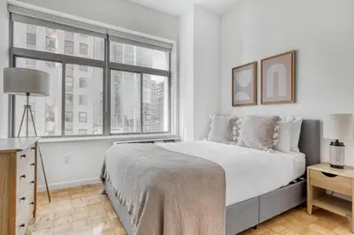 a white bedroom with a large bed and a window at FiDi 2BR w Elevator Gym Doorman nr Wall St NYC-661 in New York
