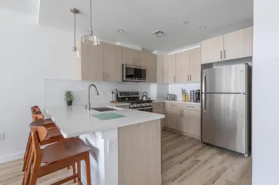 a kitchen with a stainless steel refrigerator and wooden cabinets at Modern 3BR Lofts with Outdoor Space Near NYC in Hoboken
