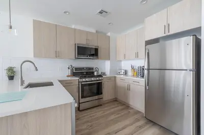a kitchen with stainless steel appliances and wooden cabinets at Modern 3BR Lofts with Outdoor Space Near NYC in Hoboken