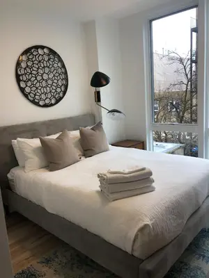 a bedroom with a bed with white sheets and a window at Modern 3BR Lofts with Outdoor Space Near NYC in Hoboken