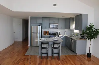 a kitchen with gray cabinets and a island with bar stools at Cozy & Deluxe Apartment - EZ Access to NYC in Newark