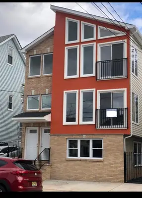 a red building with white windows on a street at Cozy & Deluxe Apartment - EZ Access to NYC in Newark