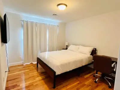 a bedroom with a bed and a desk and a television at Cozy & Deluxe Apartment - EZ Access to NYC in Newark