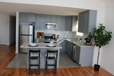 a kitchen with gray cabinets and a island with bar stools at Cozy & Deluxe Apartment - EZ Access to NYC in Newark