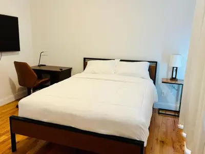 a bedroom with a large white bed and a chair at Cozy & Deluxe Apartment - EZ Access to NYC in Newark