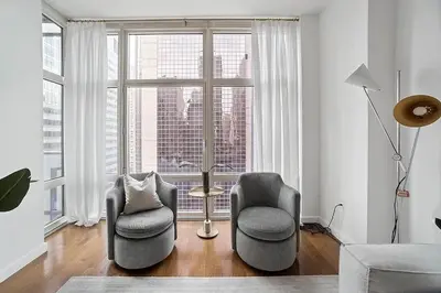 a living room with two chairs and a large window at Times Square Penthouse in New York