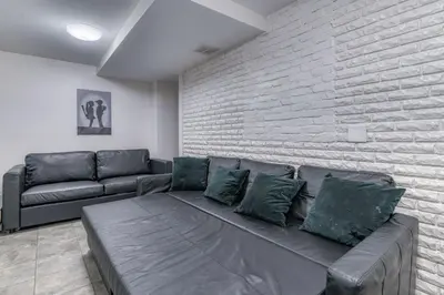 a living room with a couch and a brick wall at Gorgeous Duplex with parking by JSQ in Jersey City