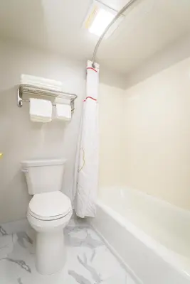 a white bathroom with a toilet and a bath tub at Philadelphia Suites at Airport - An Extended Stay Hotel in Philadelphia